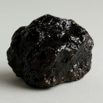 A close-up of a raw piece of Himalayan Shilajit against a neutral background