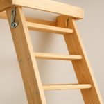 Close-up view of a wooden loft ladder with metal hooks, displayed against a neutral wall.